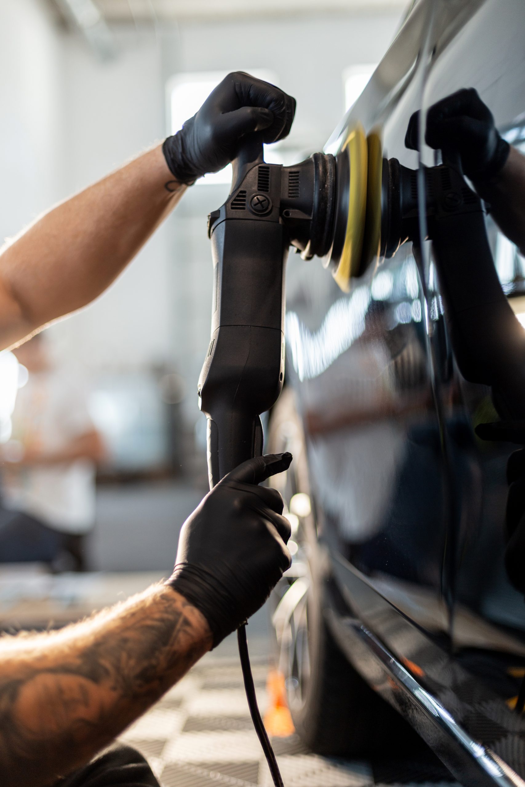 Professional man polishing black car and removing scratches in detailing center