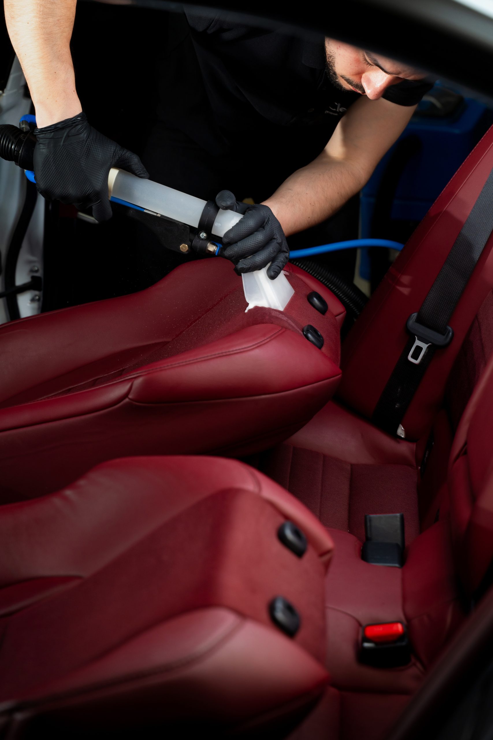 Cleaning car backseat with special vacuum nozzle. Detailing car seats with the help of vacuum extractor